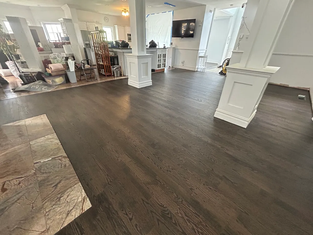 Dark gray stained hardwood in an open living area with white columns