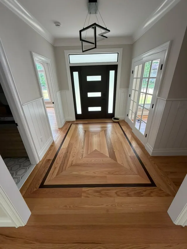 Entry foyer with a custom hardwood medallion and a black border inlay