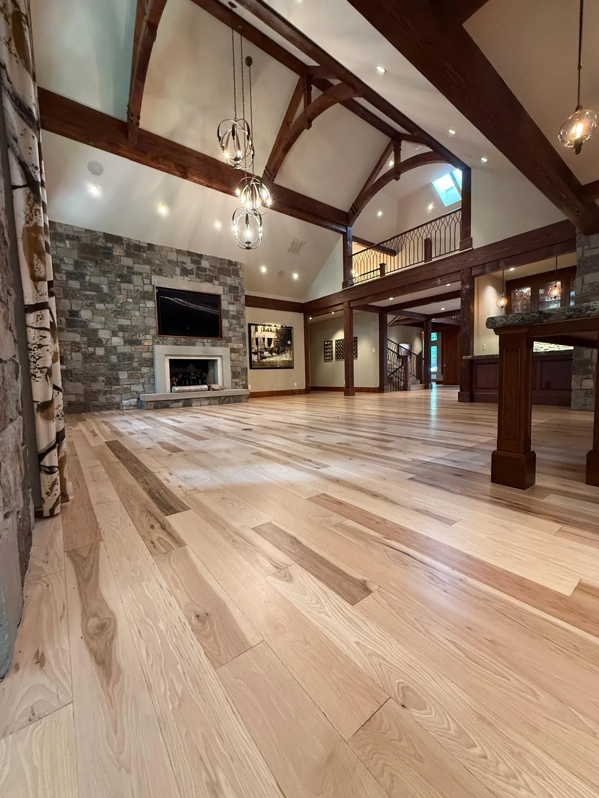 Light oak floor in a great room with a vaulted, beamed ceiling