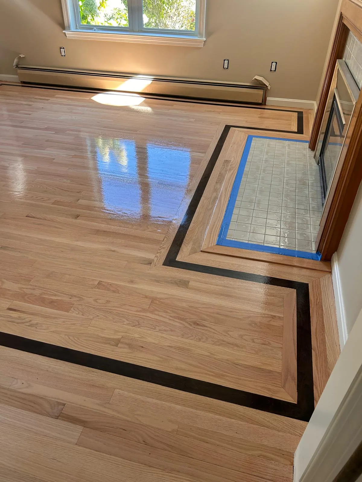 Hardwood with a black inlay framing a tiled hearth