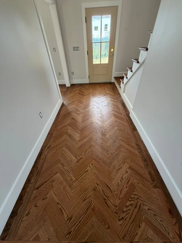 Herringbone hardwood in a long hallway by the stairs