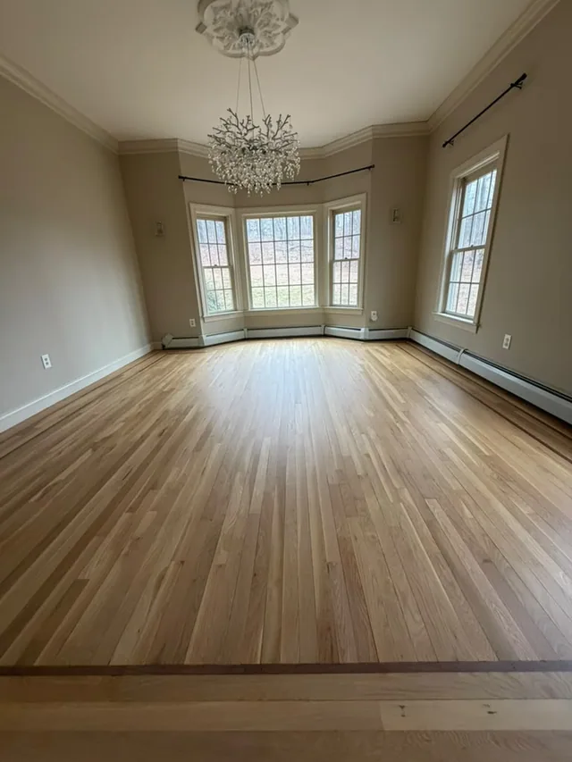 Natural oak refinish in a room with a bay window and a crystal chandelier