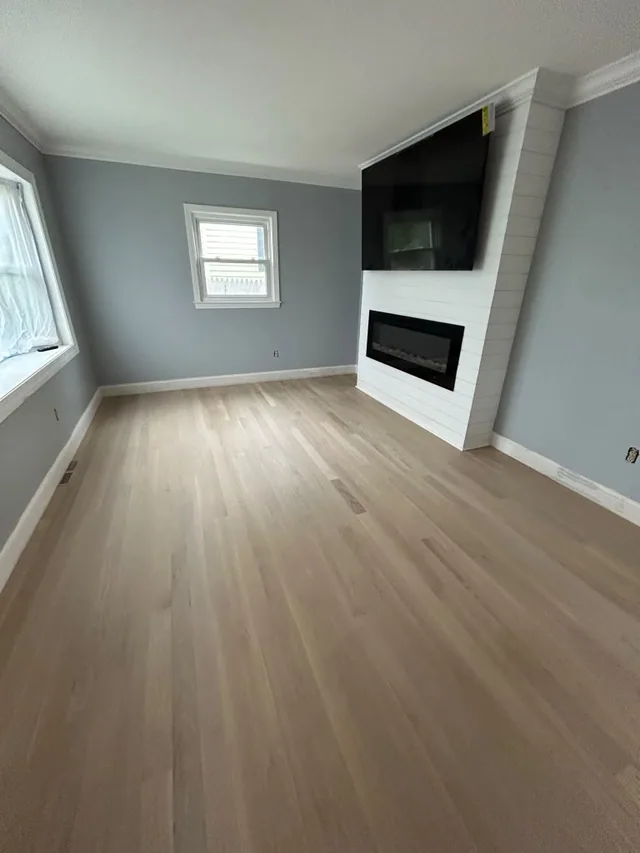 Newly installed natural oak floor in a living room with a TV and linear fireplace wall