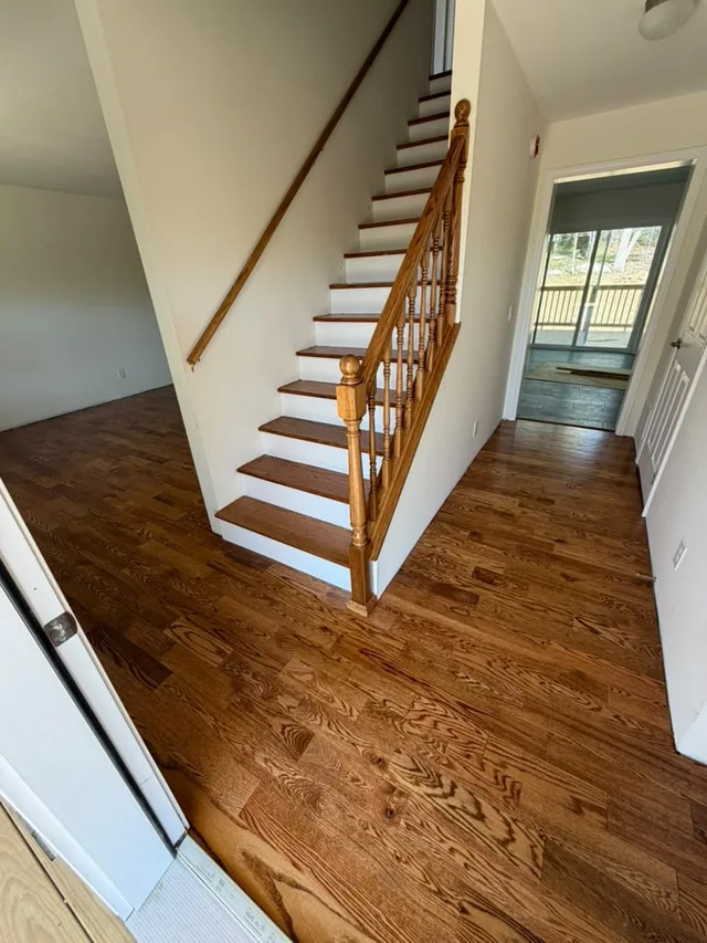 Staircase with stained oak treads and white risers over a matching oak floor